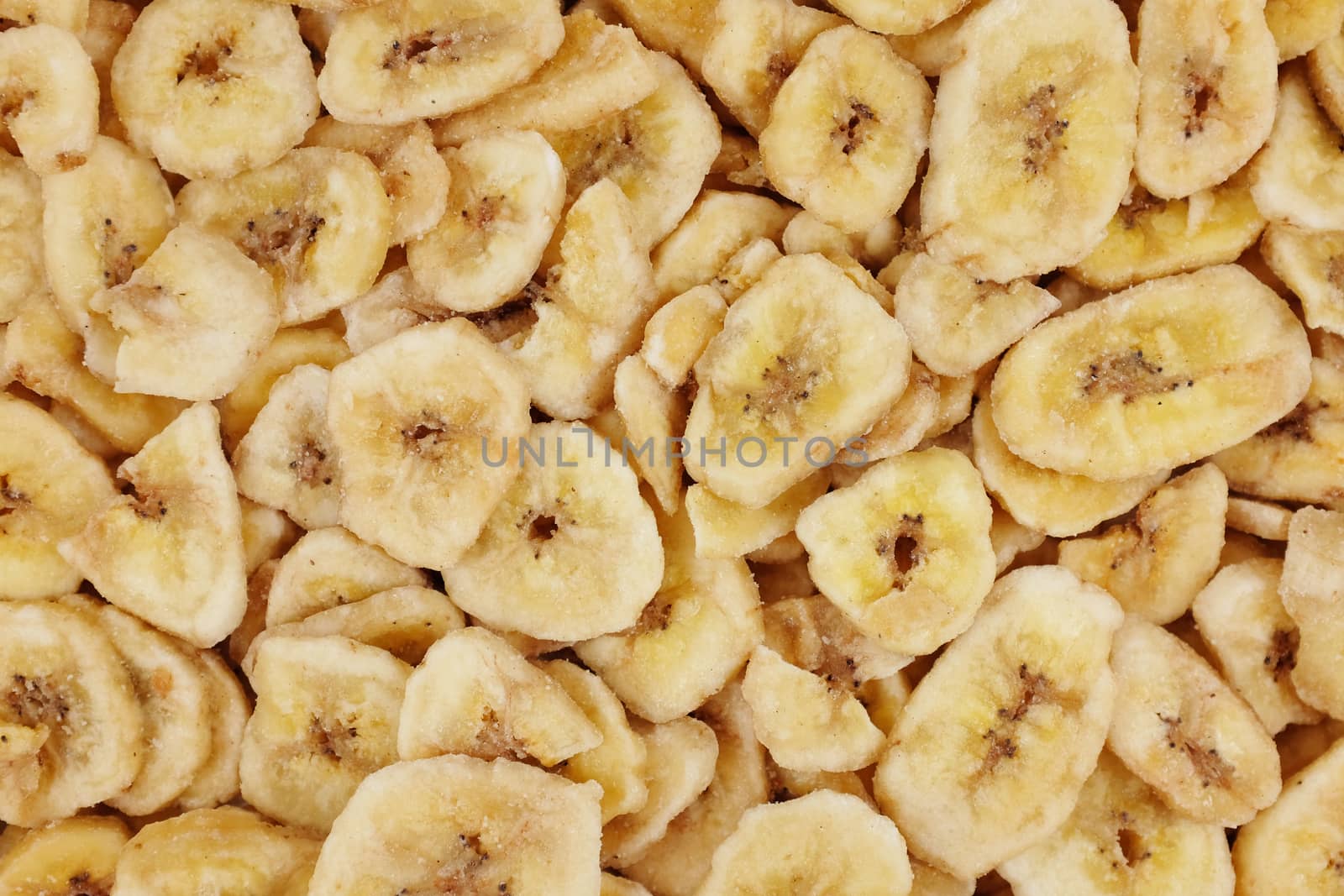 Yellow dried banana chips as an abstract background texture