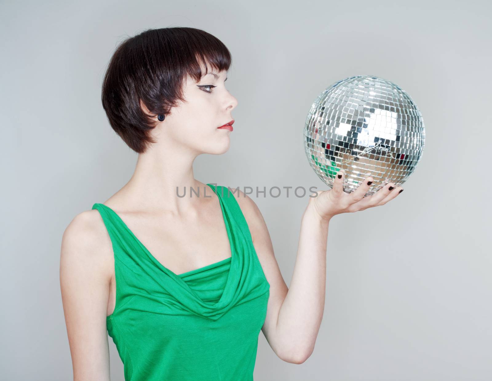 young woman holding a disco ball looking - isolated on gray