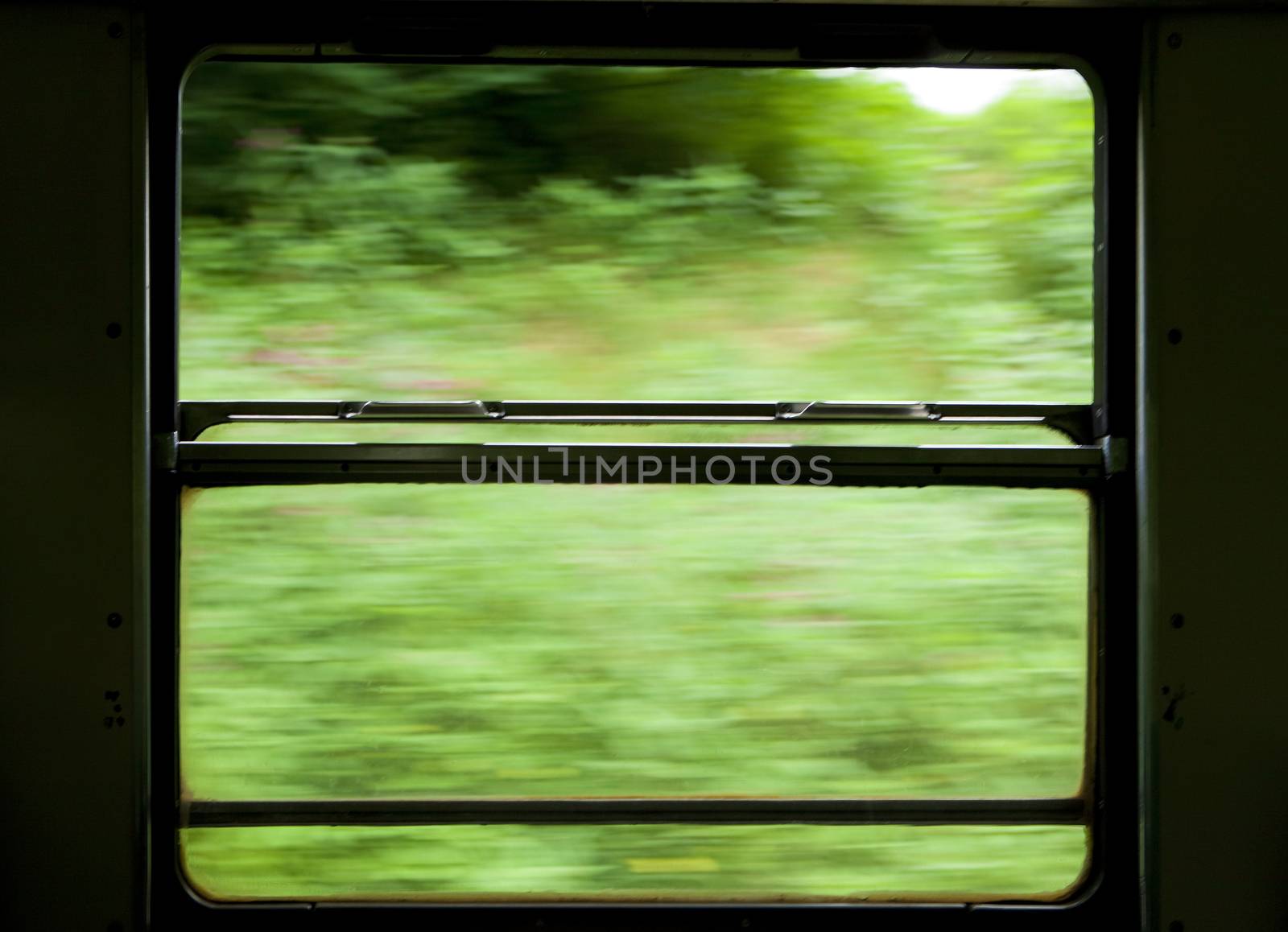 view of moving train window from the inside showing landscape outside