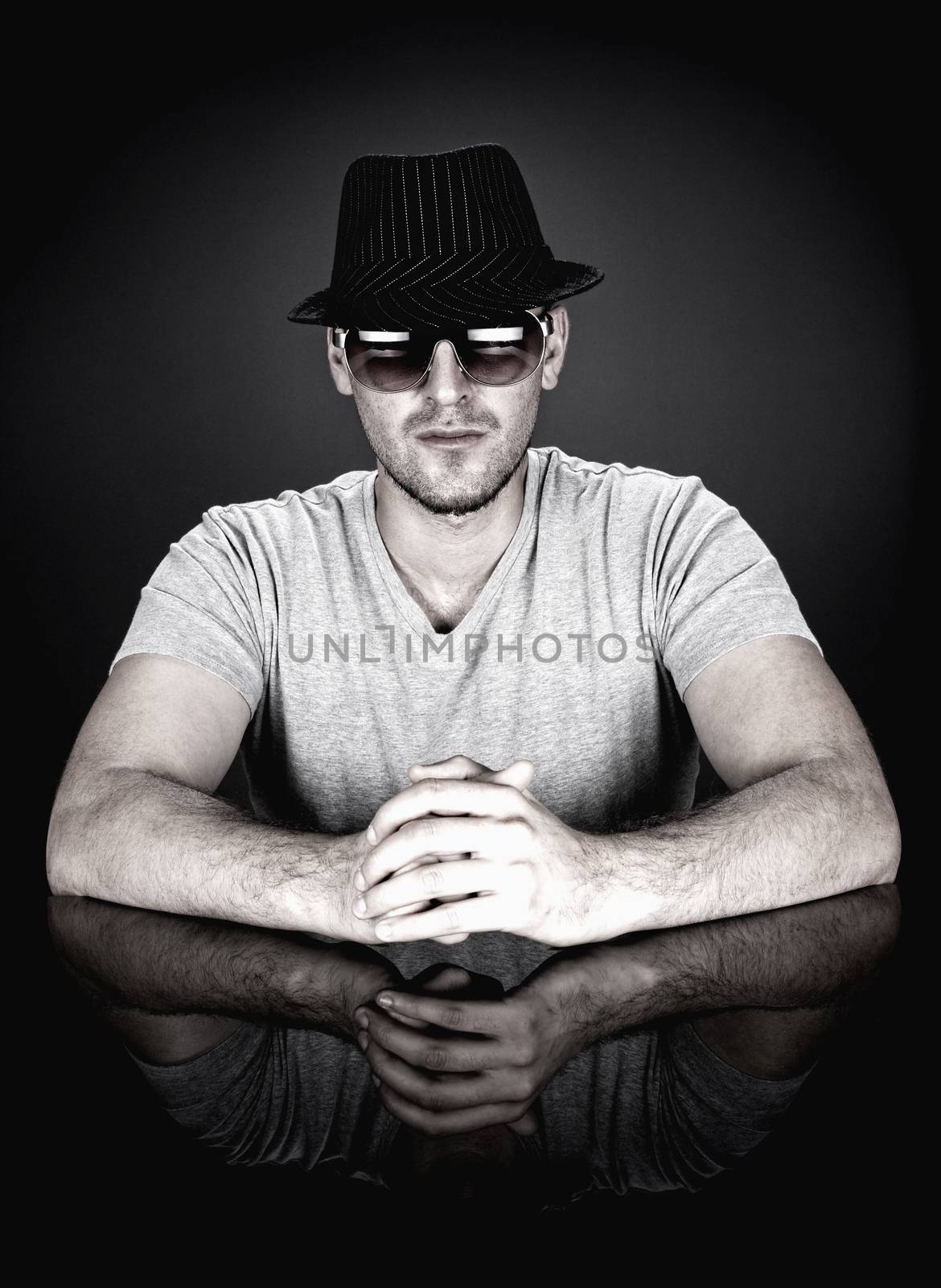 man in hat and sunglasses sitting behind desk looking at camera