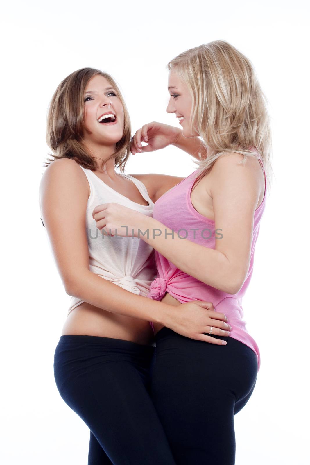 two young happy female friends standing laughing - isolated on white