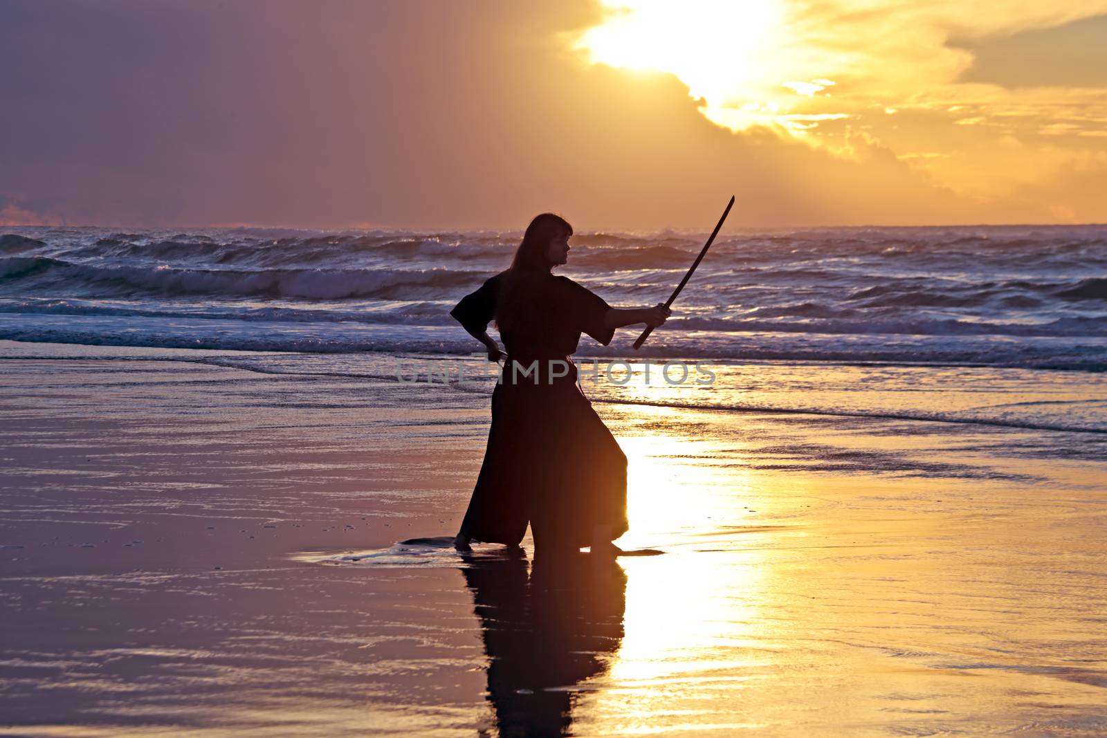 Young samurai women with Japanese sword(Katana) at sunset on the beach