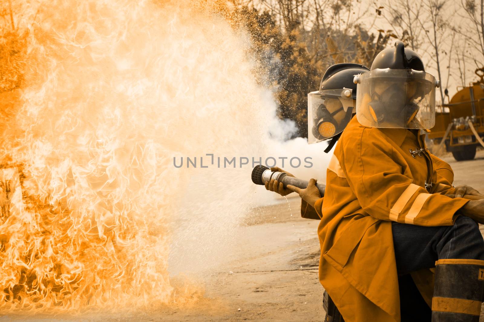Firemen in action fighting fire during training by Thanamat