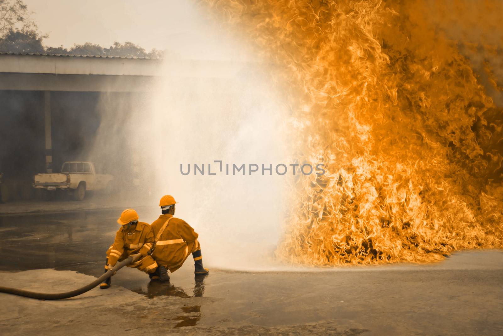 Firemen in action fighting fire during training by Thanamat