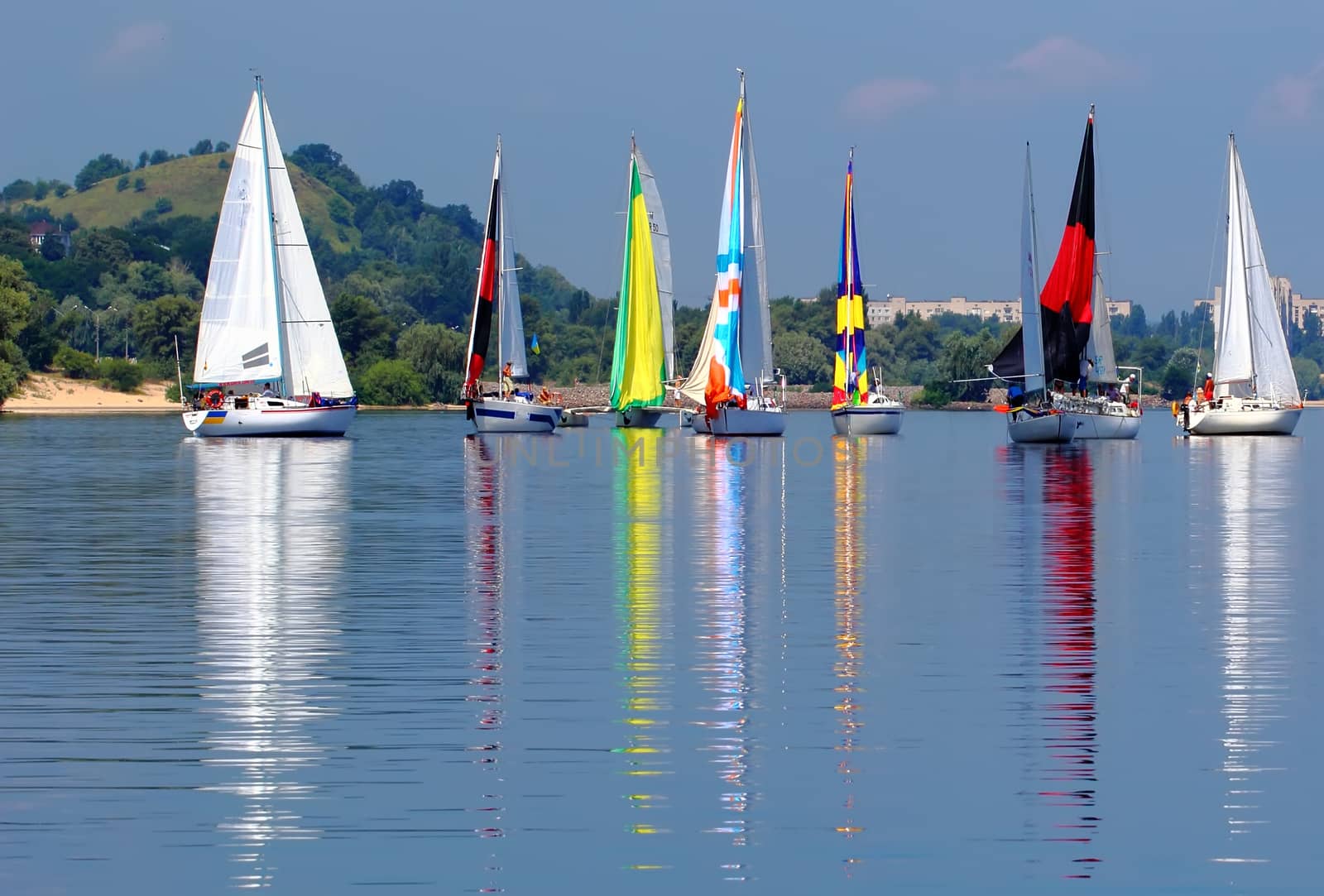 sailboats with colorful sails near the mountain