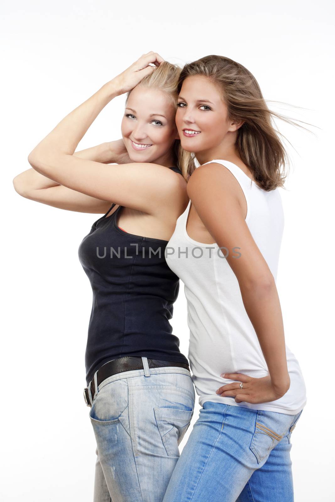two young happy female friends standing smiling - isolated on white