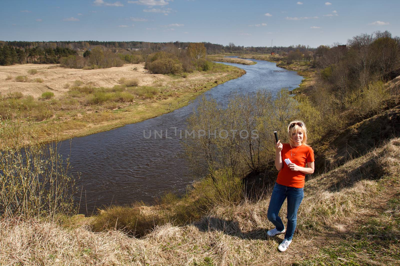 A woman by a river in a unpopulated area playing Geocaching