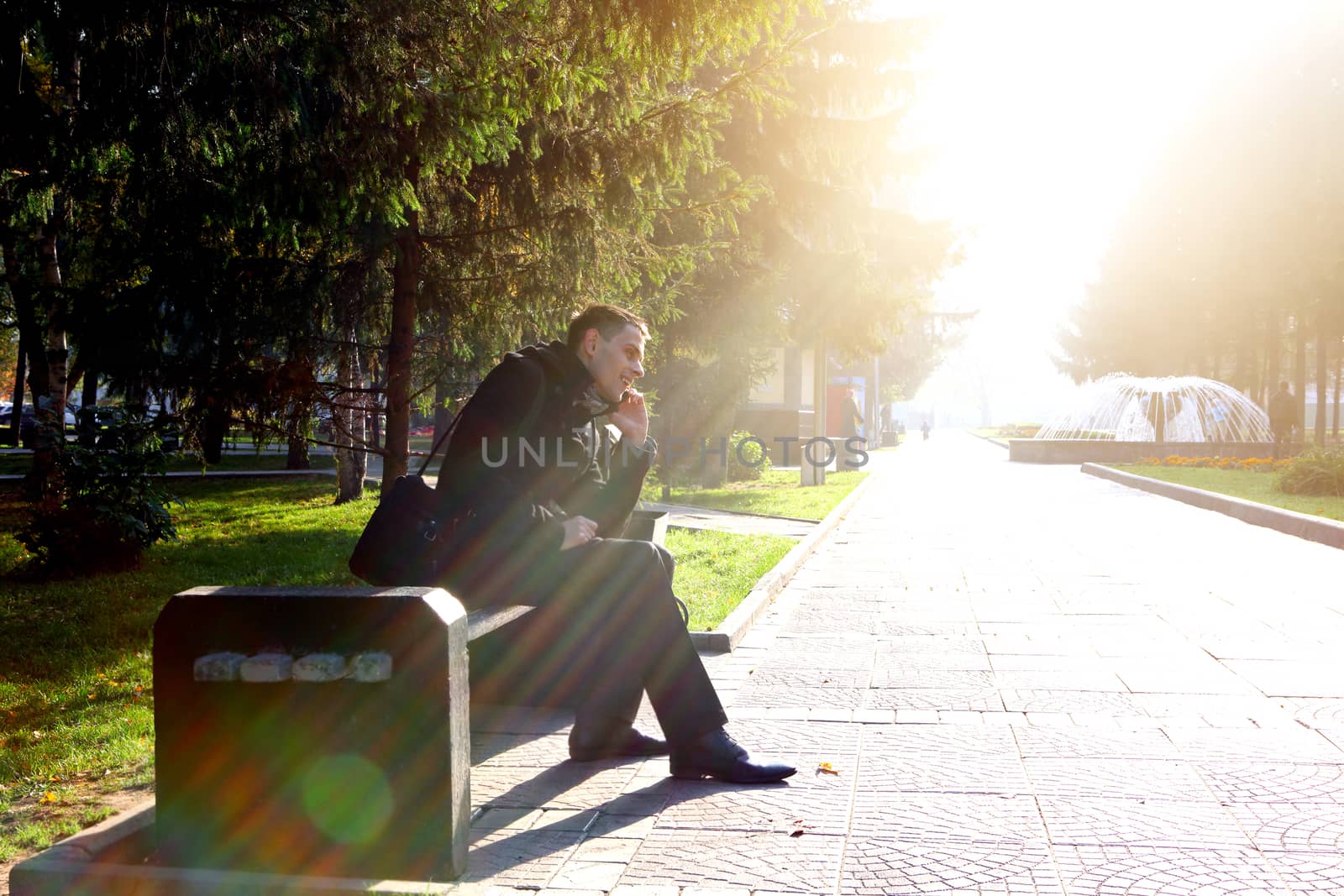 Toned photo of Cheerful Young Man with Mobile Phone at the Autumn Park