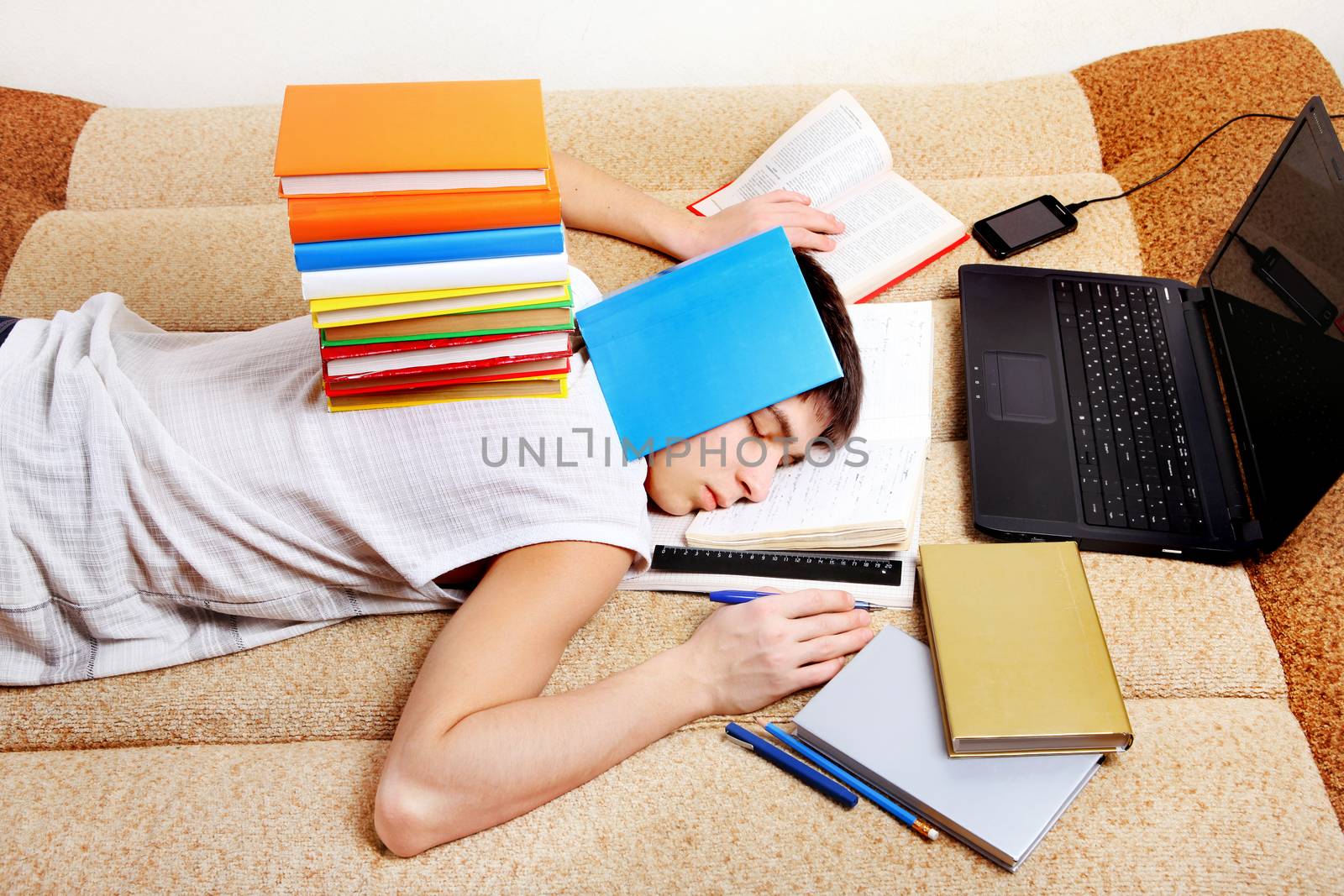 Tired Teenager sleeping on the Sofa with the Books