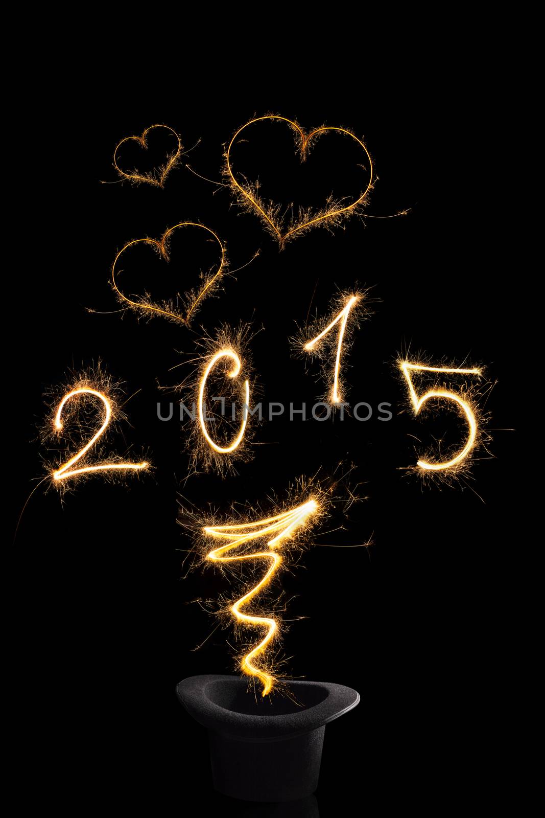 Magical happy new year. Magical fireworks from black top hat forming digits 2015, heart shapes and abstract light lines isolated on black background. Happy new year background.