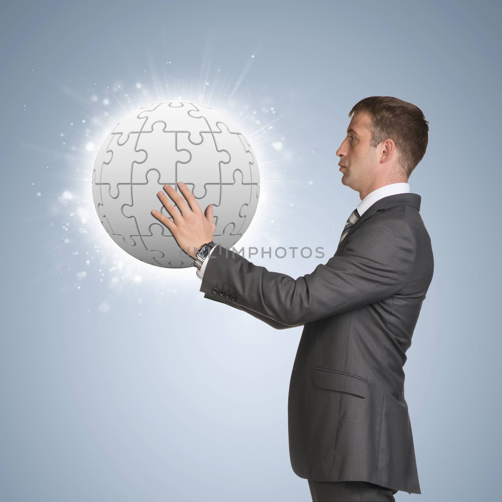 Businessman in suit hold jigsaw puzzle sphere by cherezoff