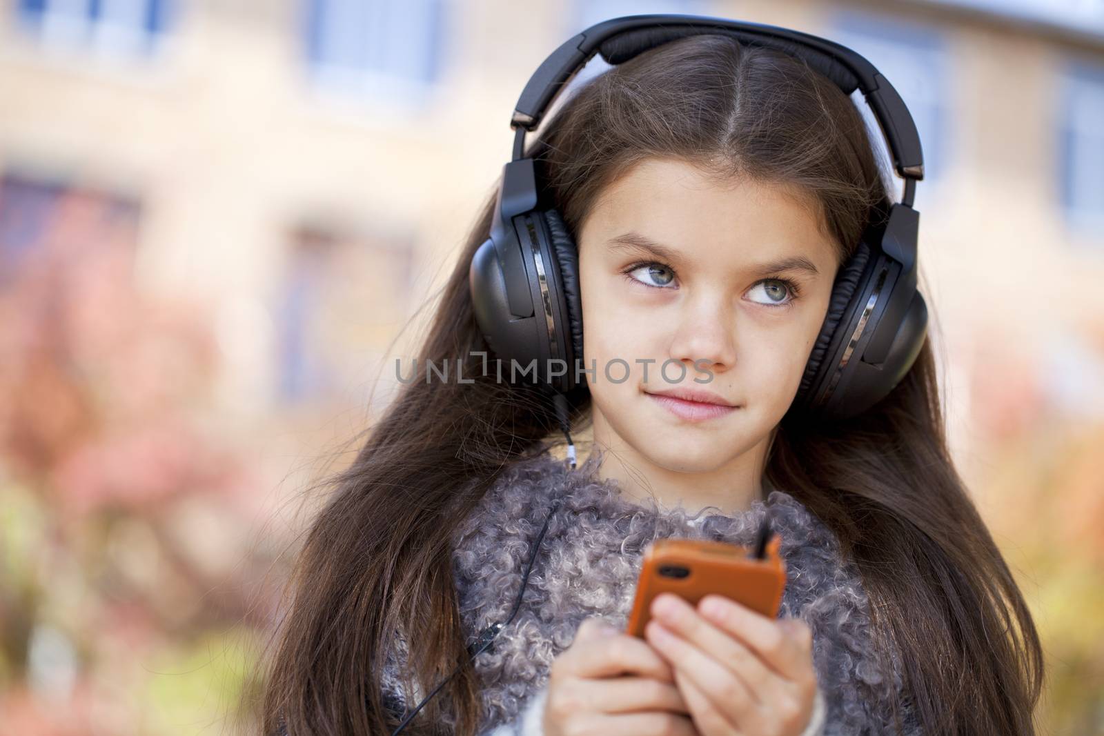 Beautiful little girl listening to music on headphones by andersonrise
