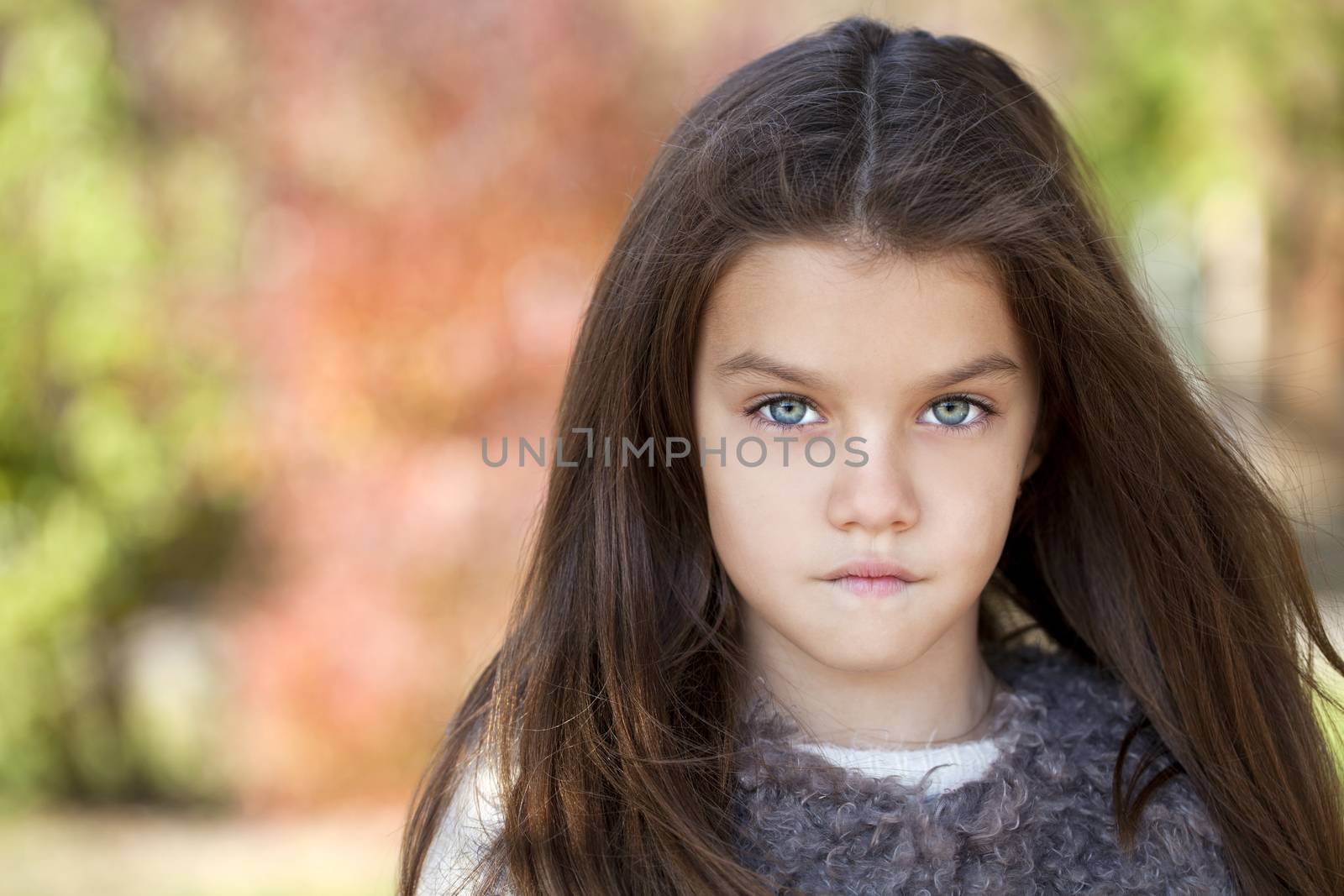 Close up portrait of a beautiful nine year old little girl in autumn park