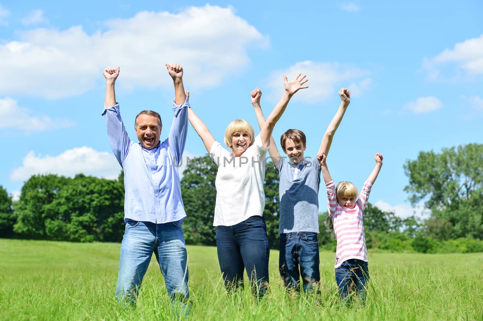 Happy family together raising their arms by stockyimages