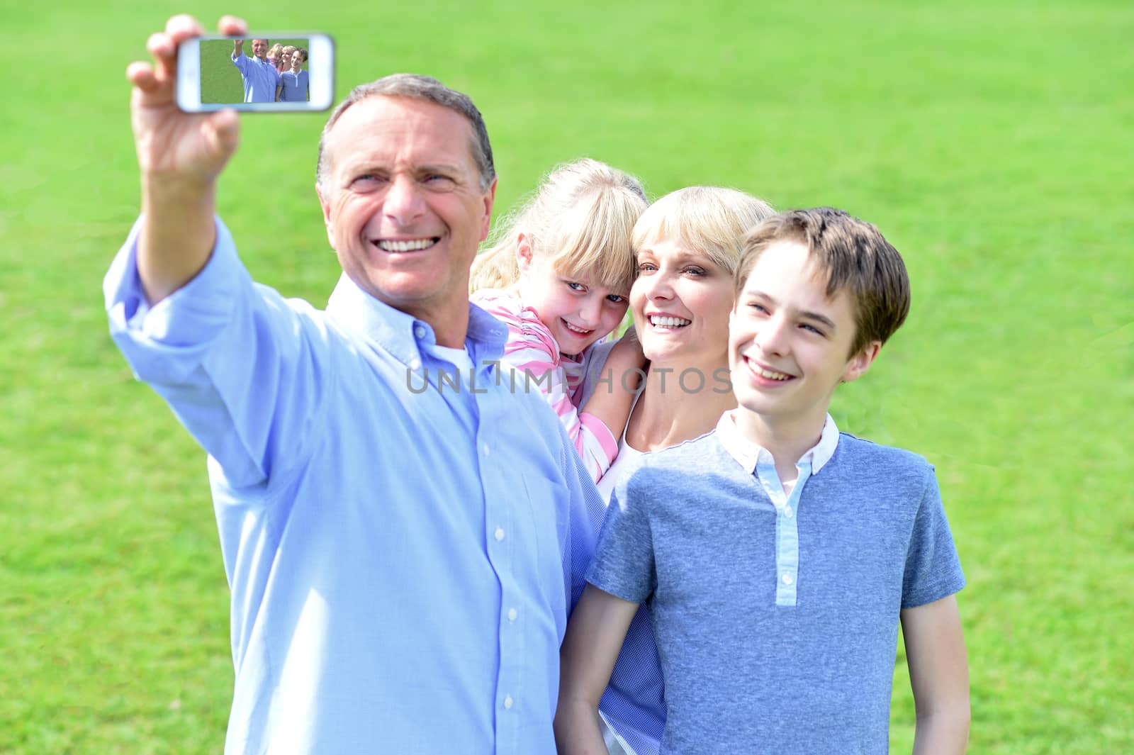 Smiling family of four taking selfie with smartphone