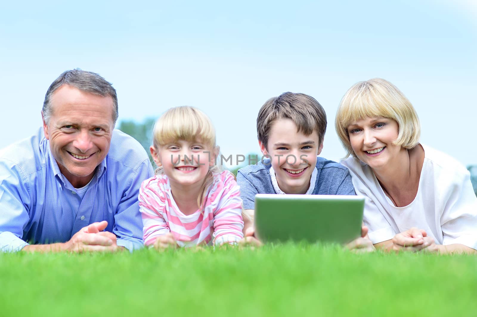 Smiling couple together with children lying on park