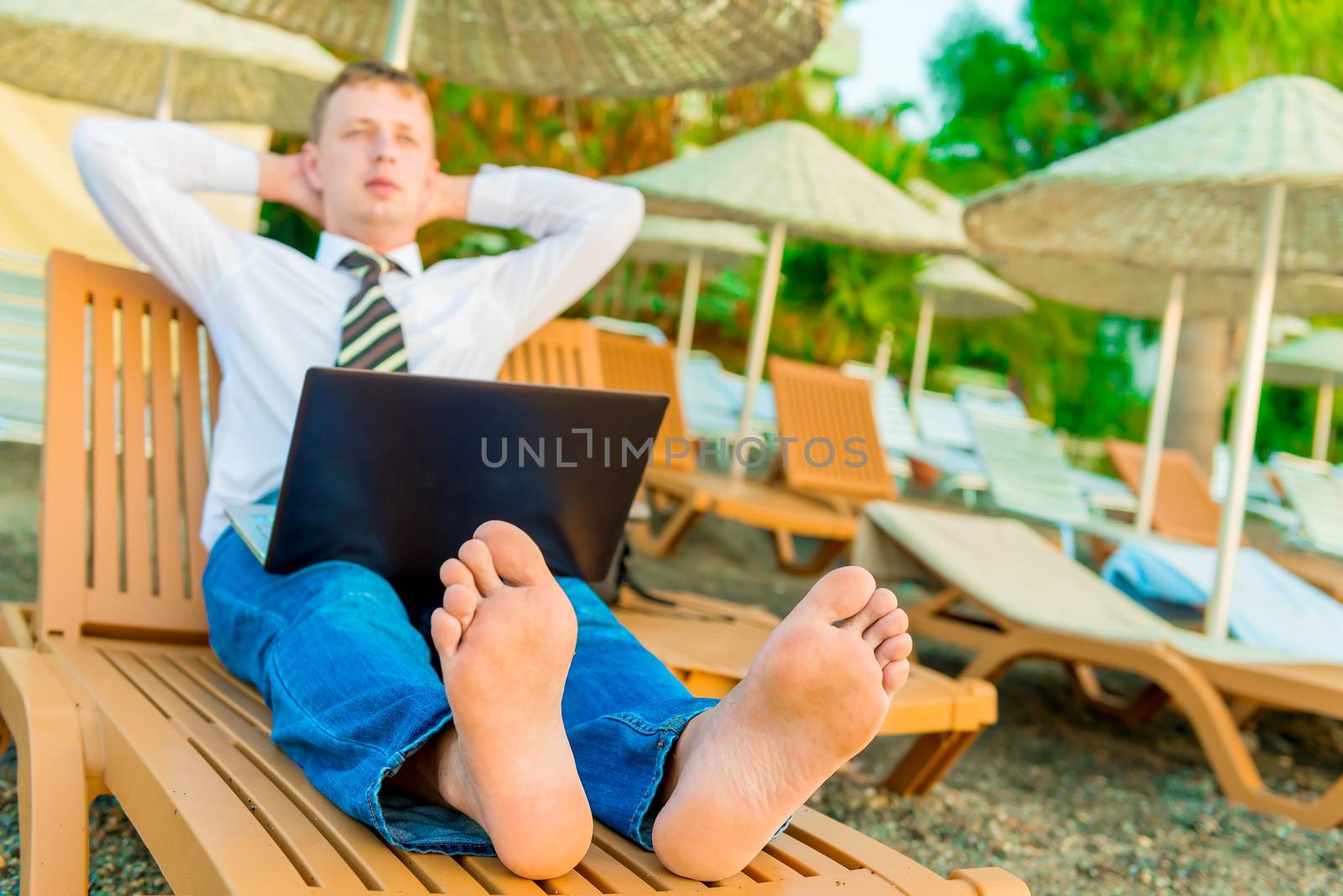 barefoot manager on a sun lounger with a laptop by kosmsos111