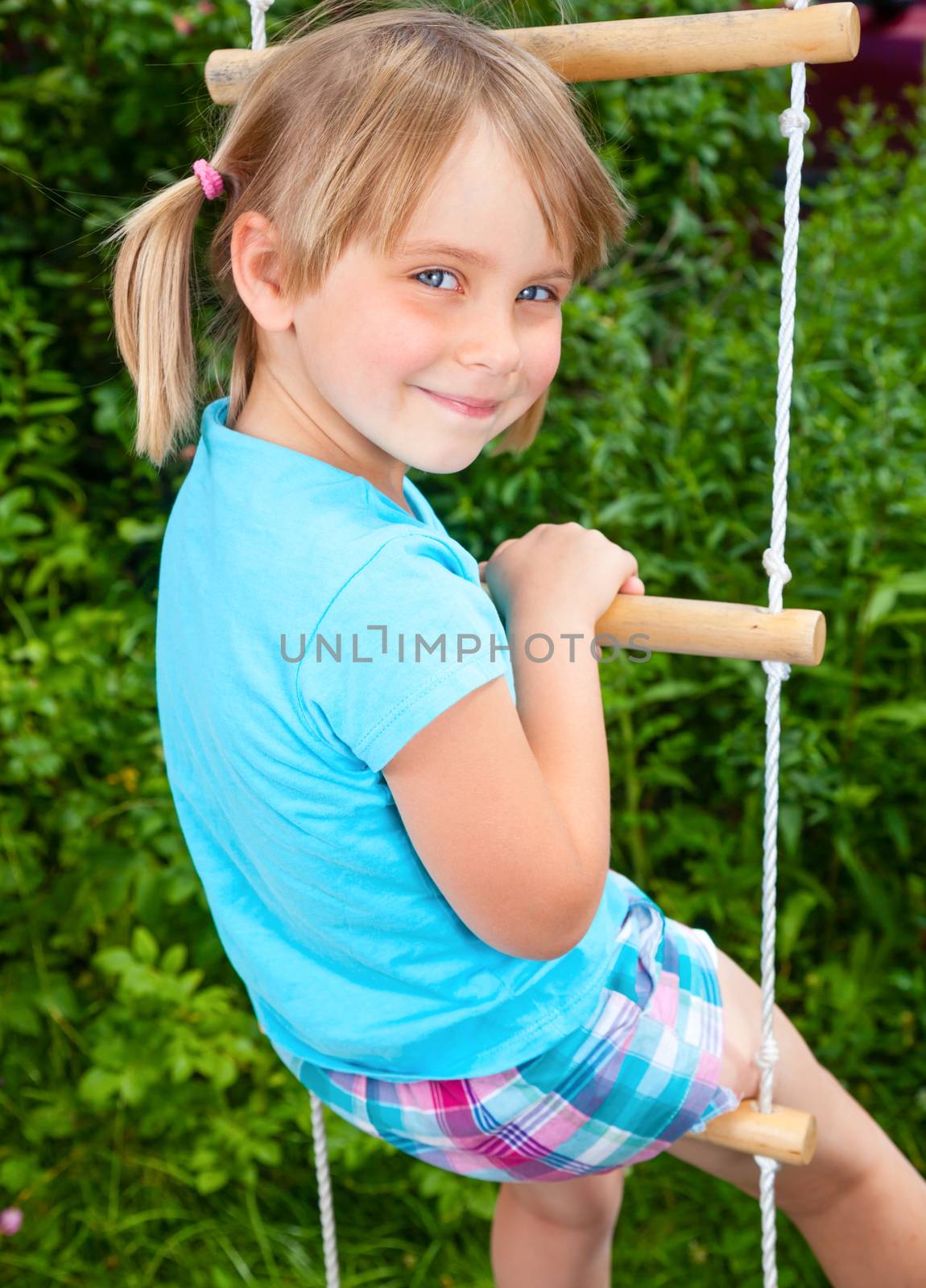 Portrait of cute little girl playing at monkey bars