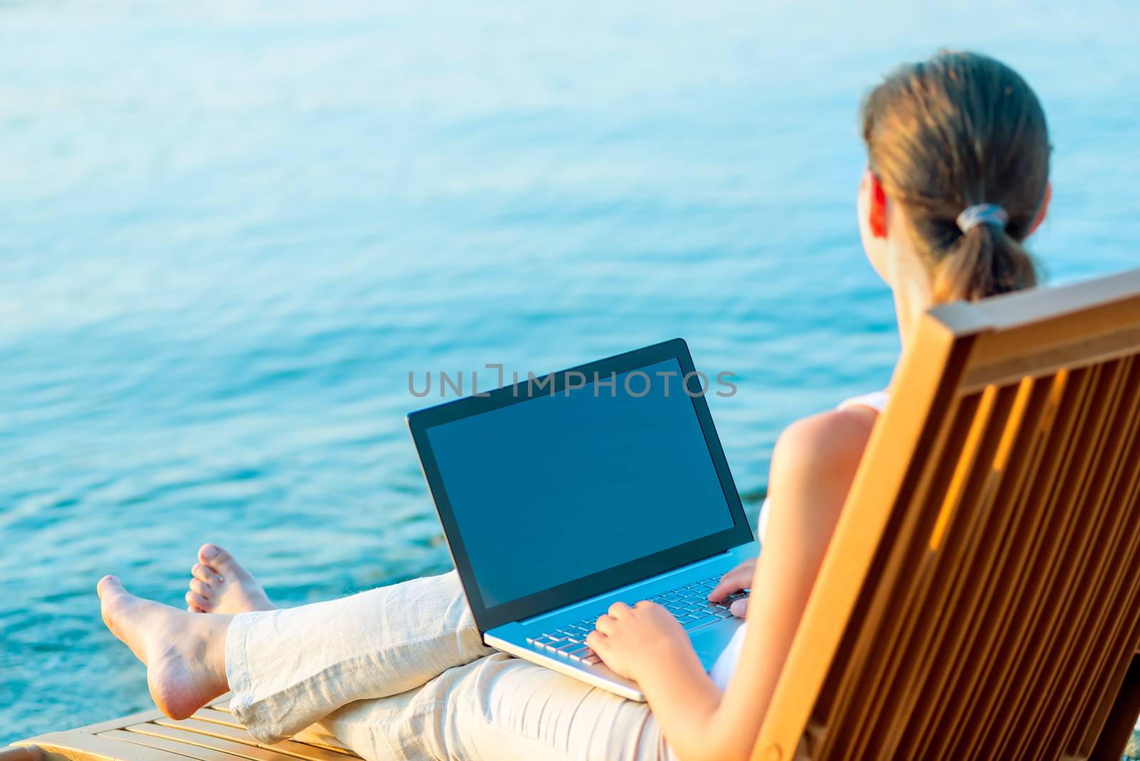 barefoot girl with a laptop on the beach working