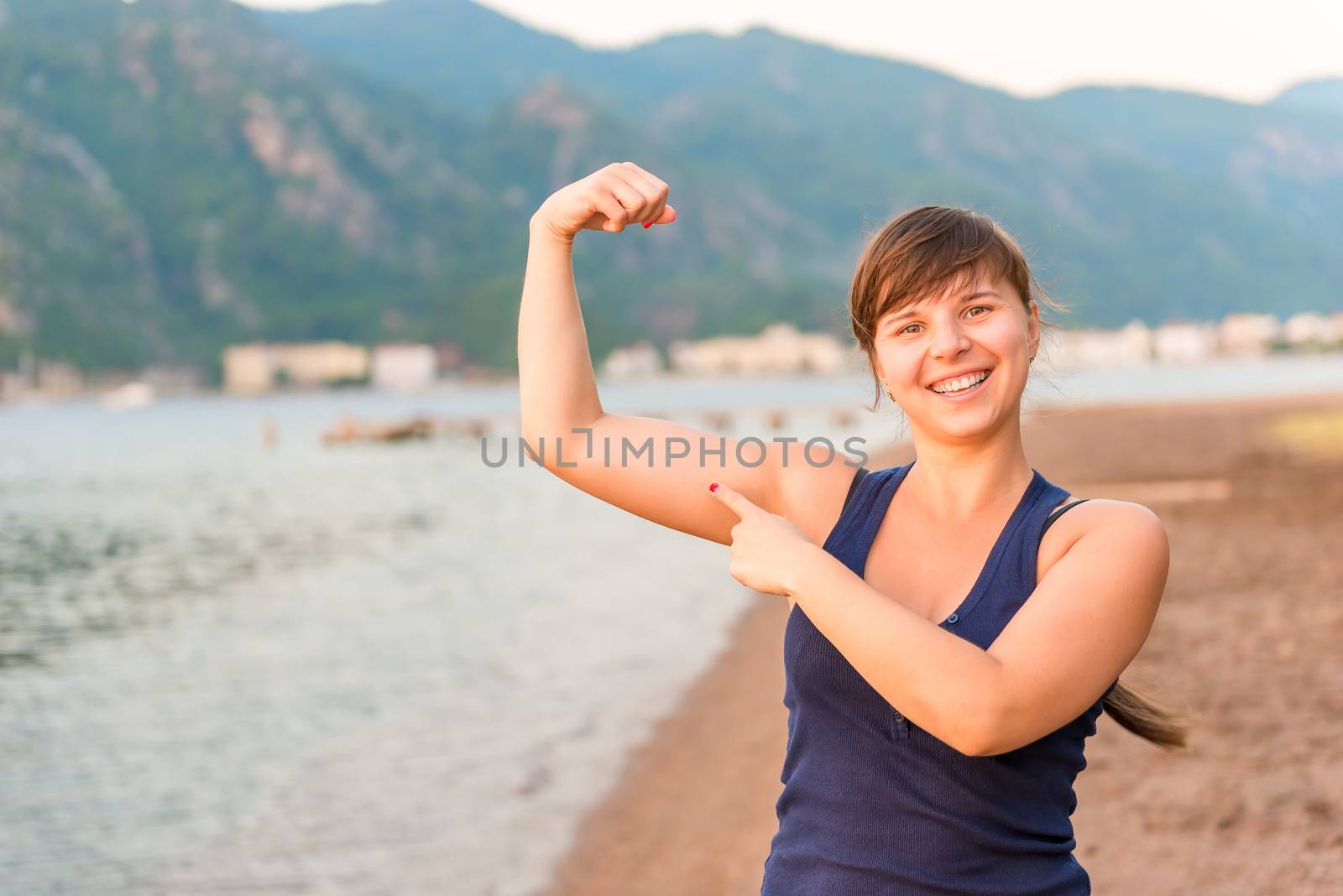 happy girl showing muscles on the beach