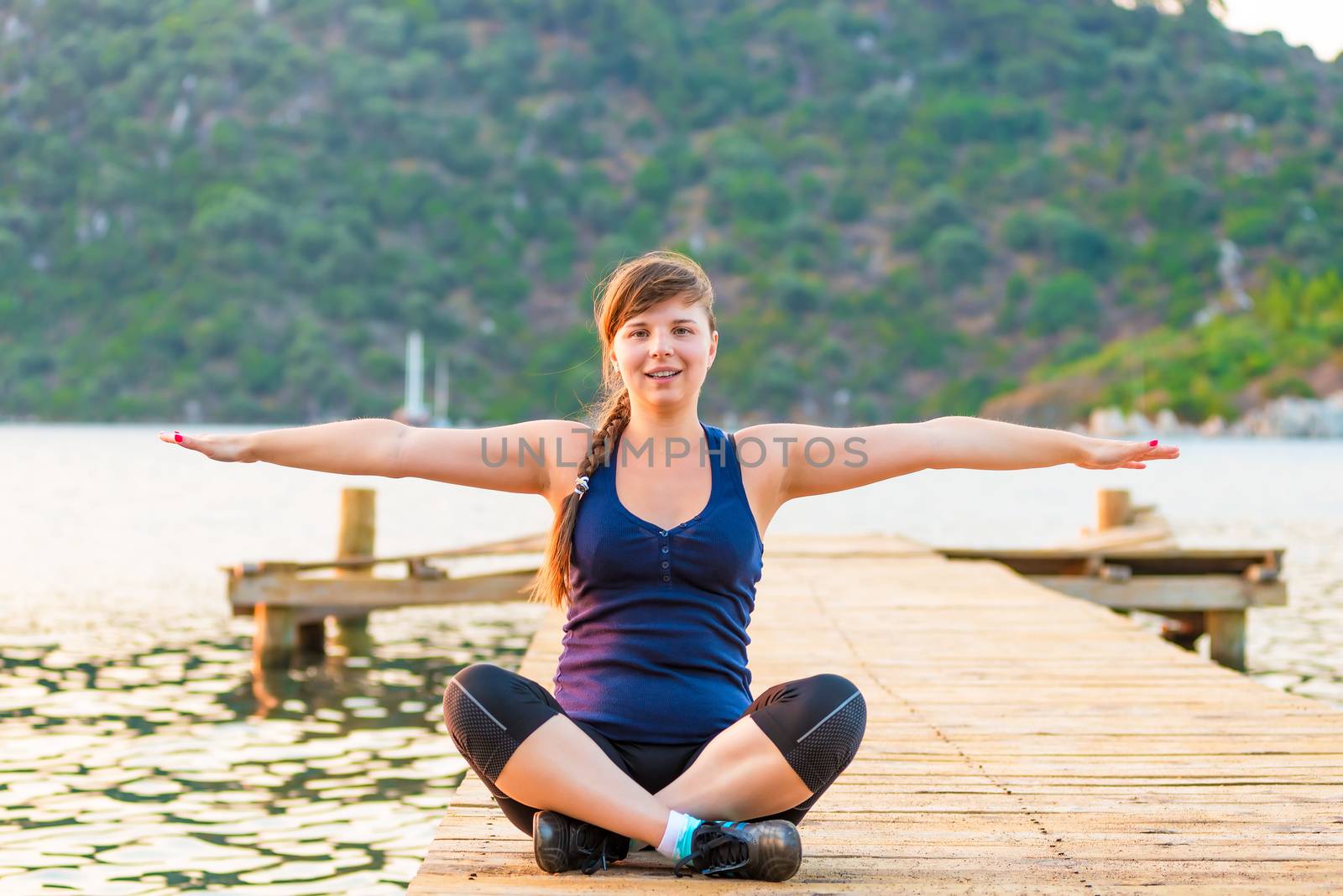 relaxed girl on a pier in the lotus position by kosmsos111