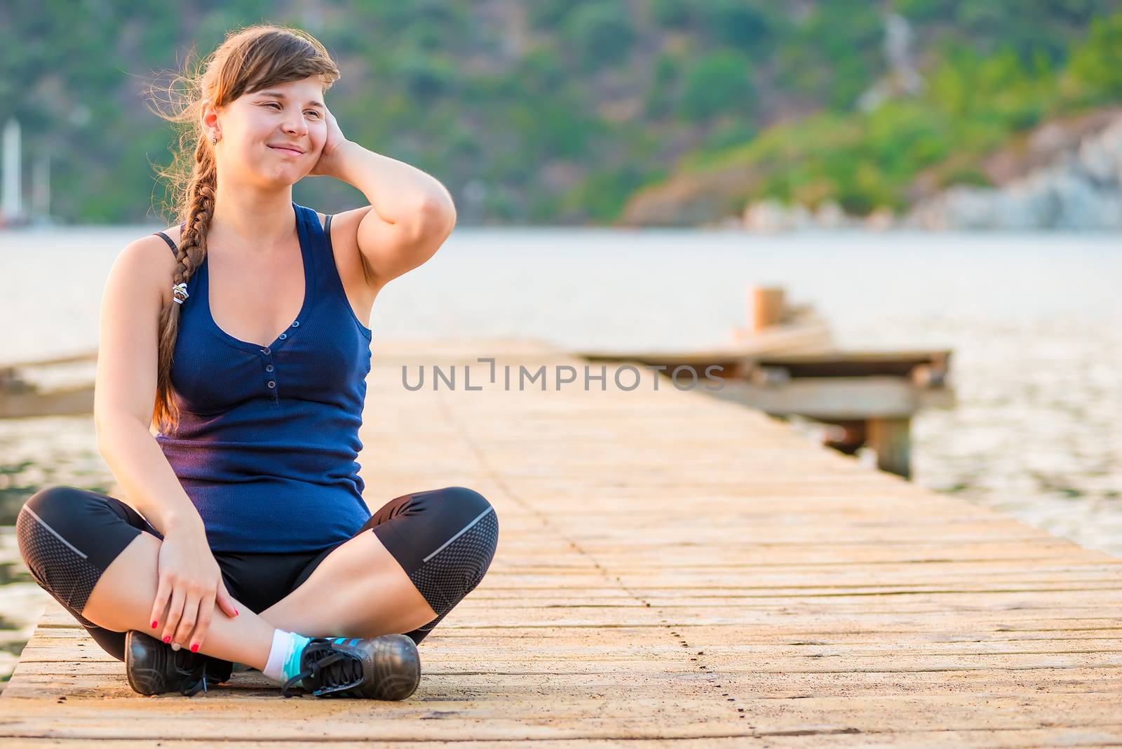 brunette with long braid smiling sitting on the pier