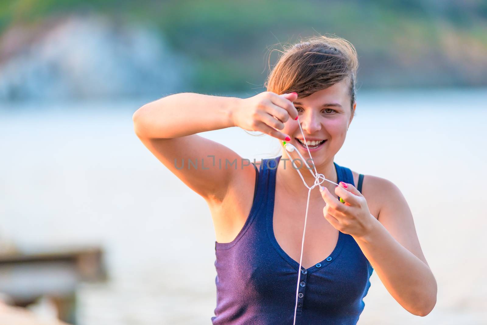 smiling young woman unravels headphones by kosmsos111