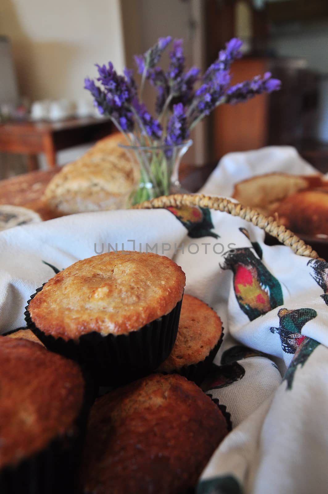 Freshly baked breakfast muffins in a basket with other home baked produce in the background.