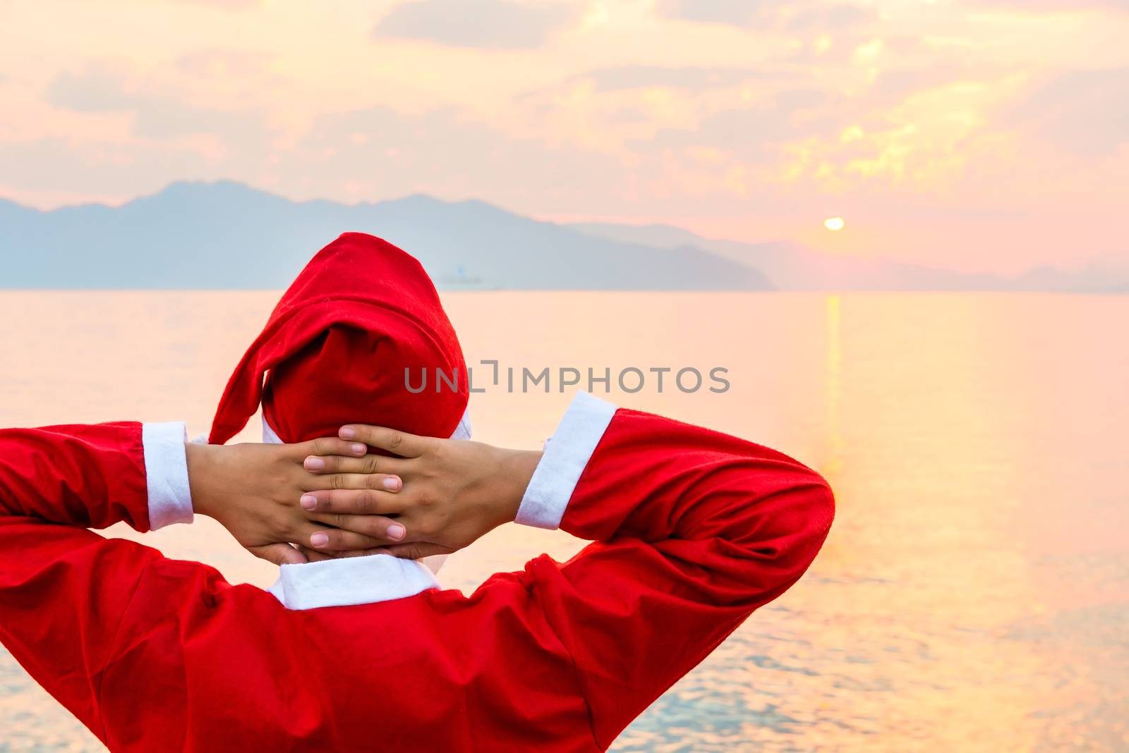 Santa Claus looking at the sunrise over the sea