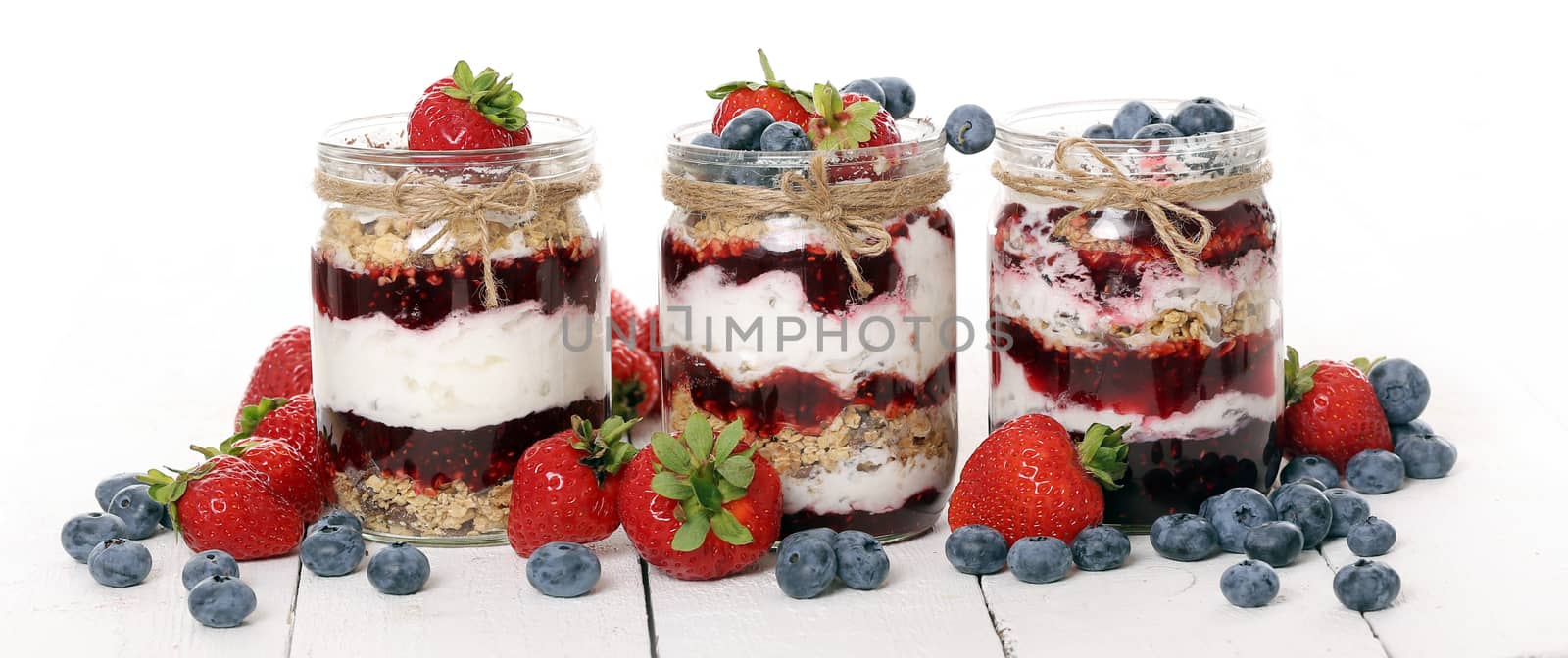 Picture of jars with different berries over a white background