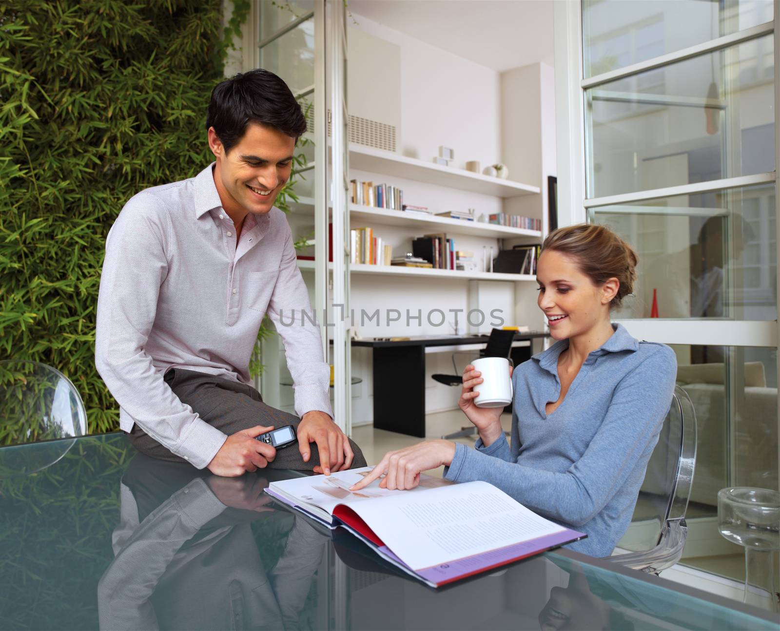 Happy young casual couple sitting at desk working together at home