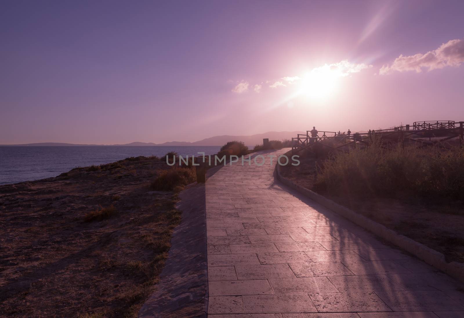 Sea promenade with low afternoon sun and jogger through Es Carnatge, Mallorca, Balearic islands, Spain.
