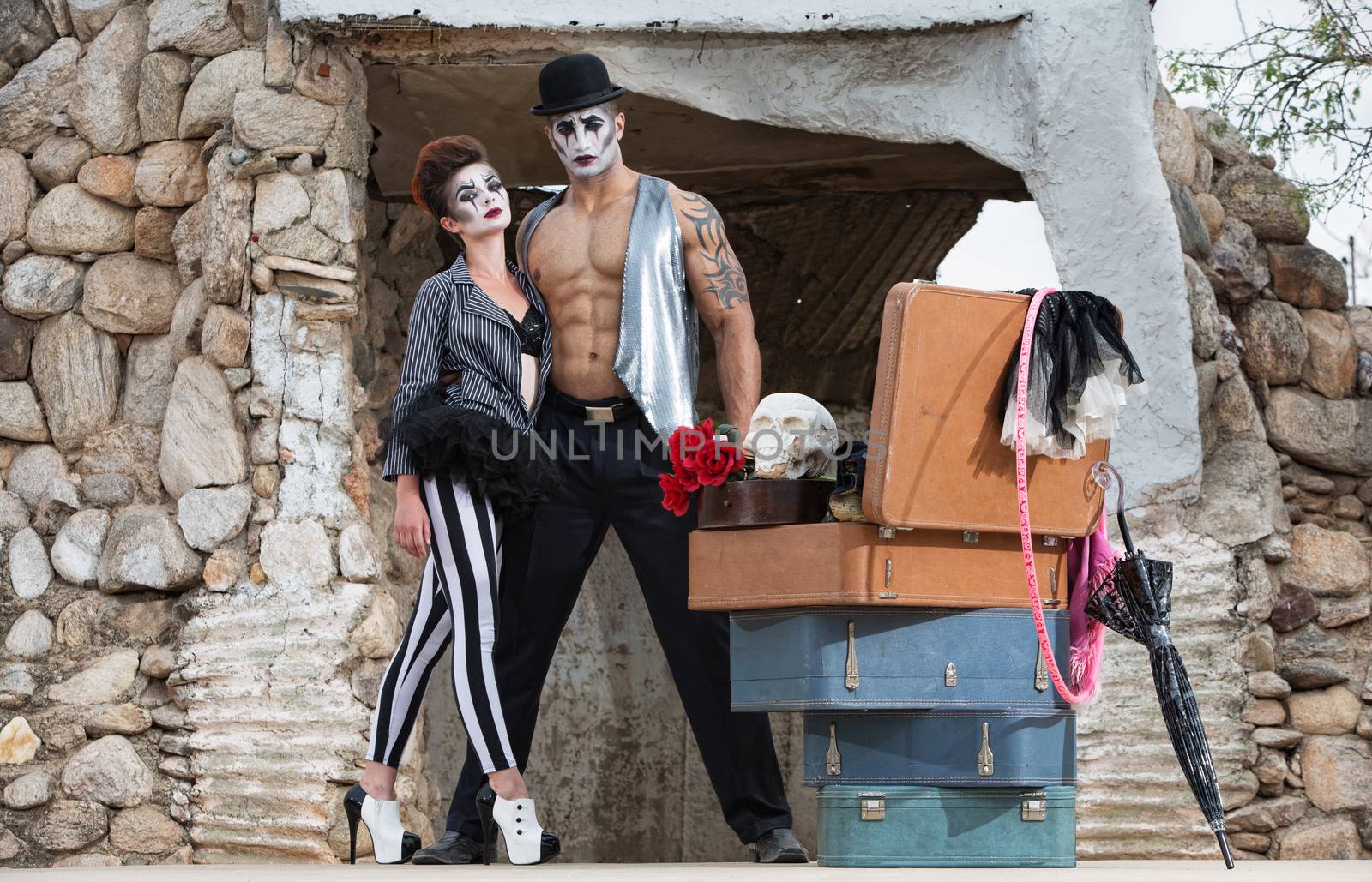 Muscular cirque performer with bizarre female partner in striped pants