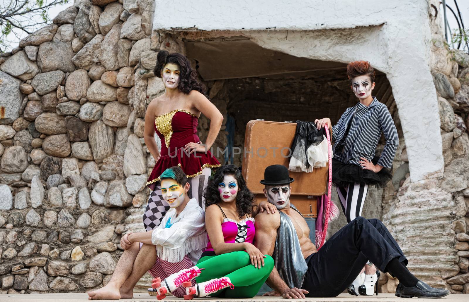 Group of male and female comedia del arte performers sitting on stage