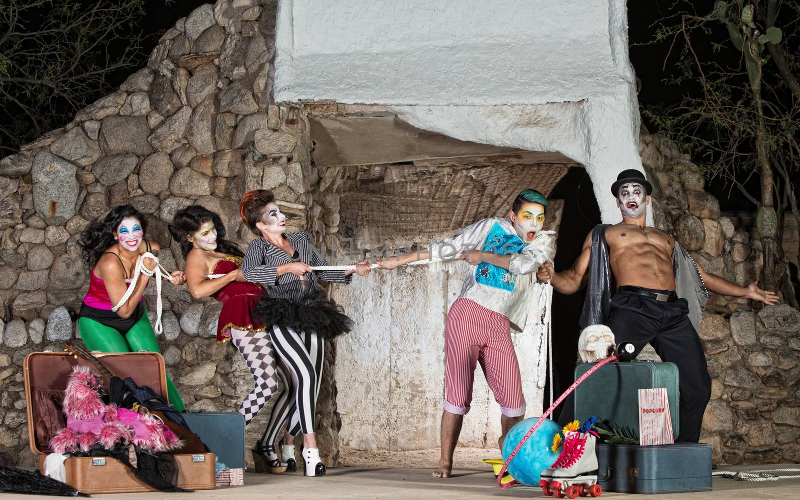 Group of silly cirque clowns playing tug-of-war