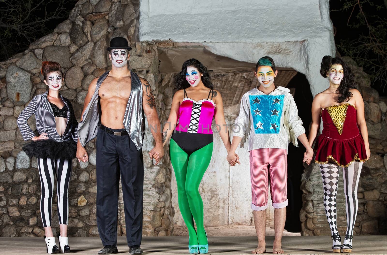 Group of mixed cirque clowns bowing on stage