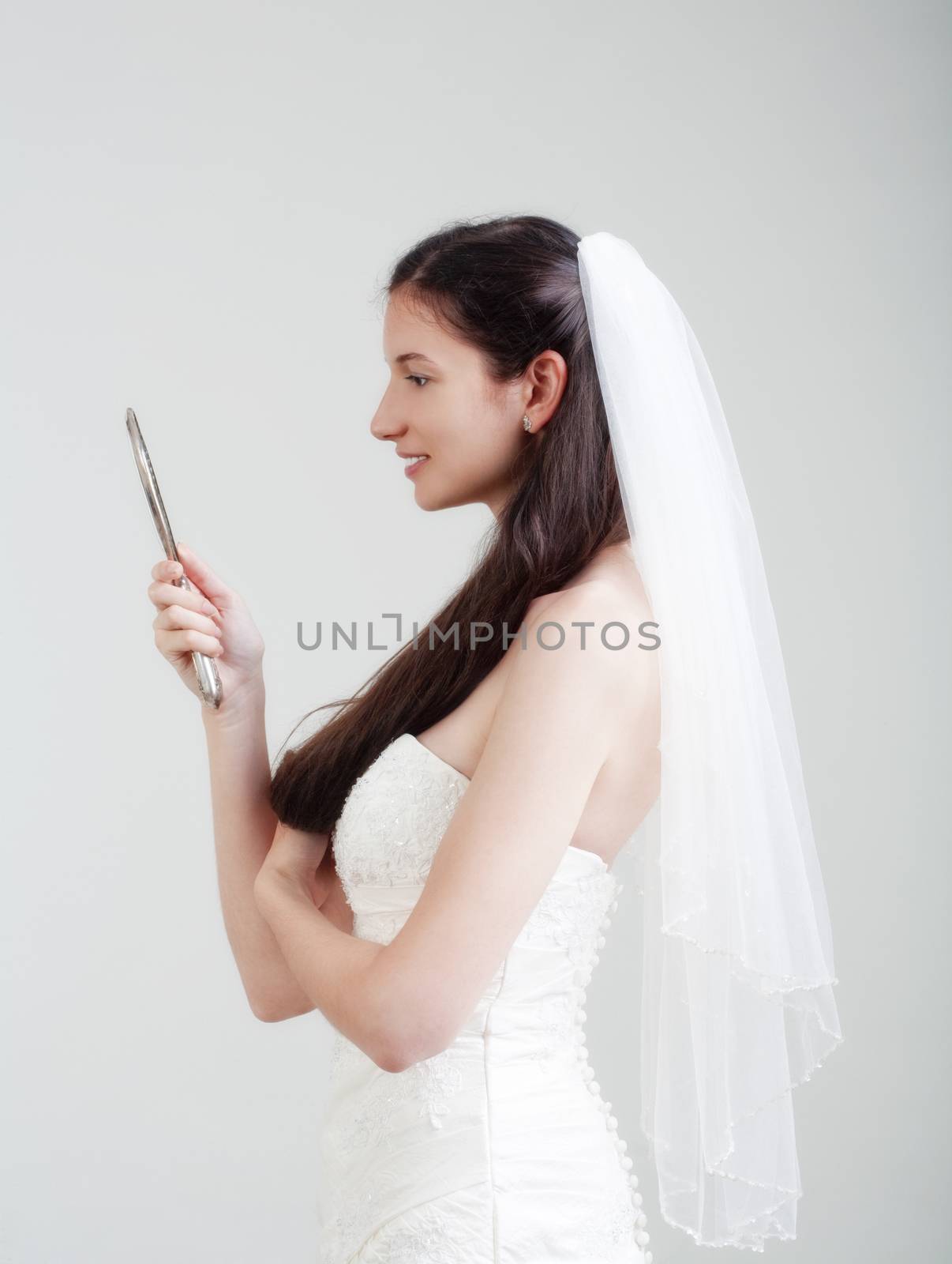 portrait od a bride with long dark hair in wedding dress - isolated on gray