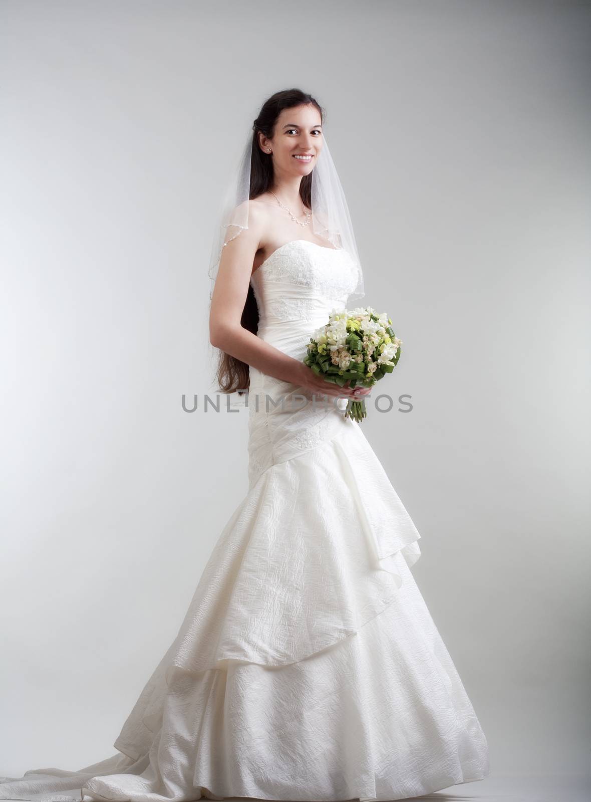 portrait od a bride with long dark hair in wedding dress - isolated on gray