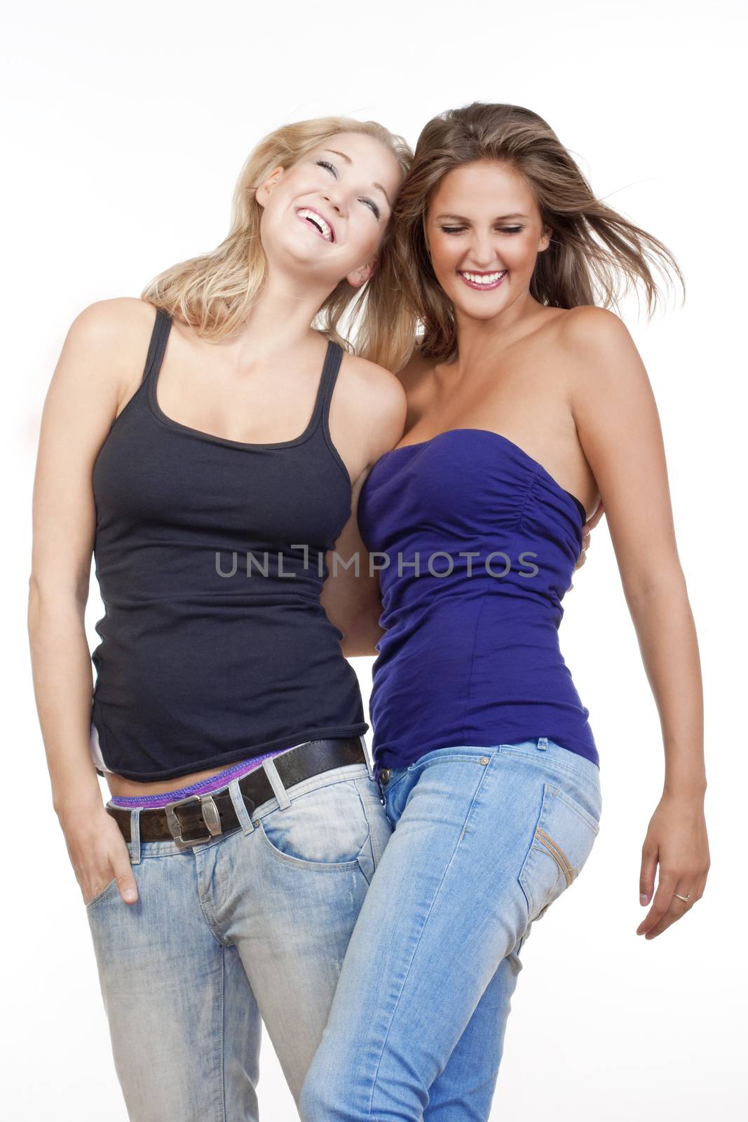 two young happy female friends standing smiling - isolated on white