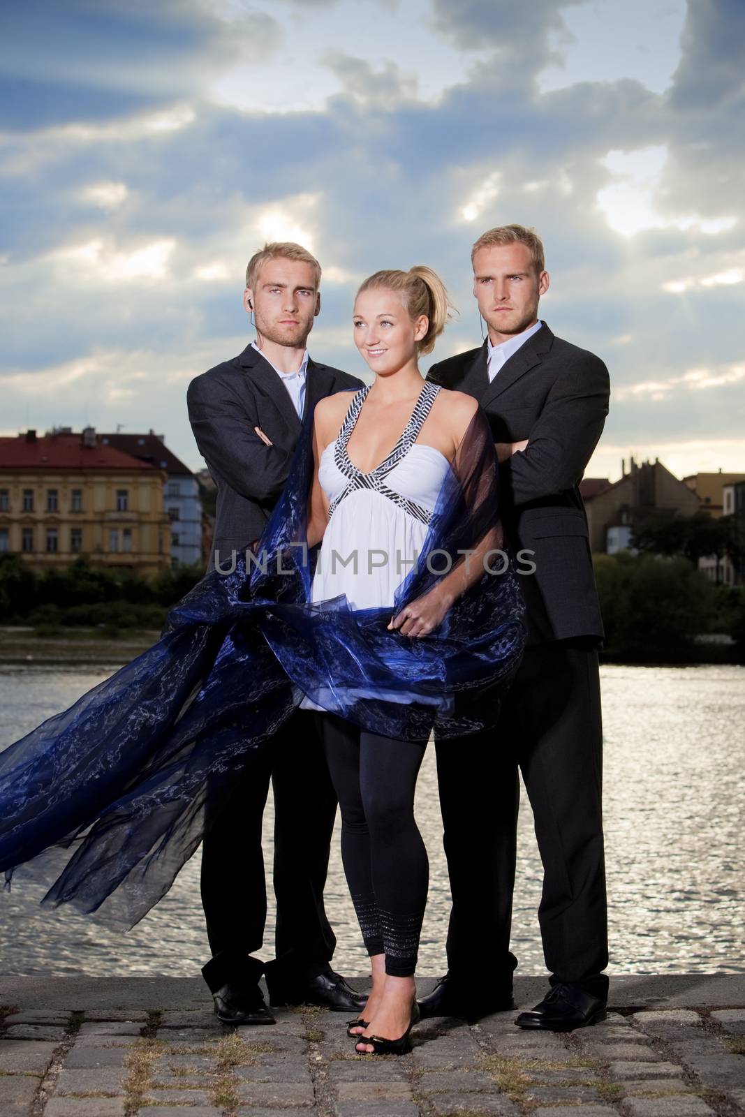 beautiful young blond woman standing outdoors accompanied by two bodyguards