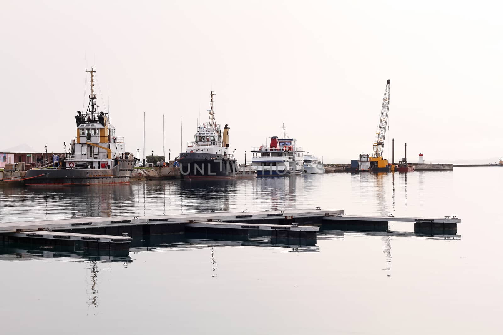 A fleet of pilot boats against a harbour wall, on a hazy day