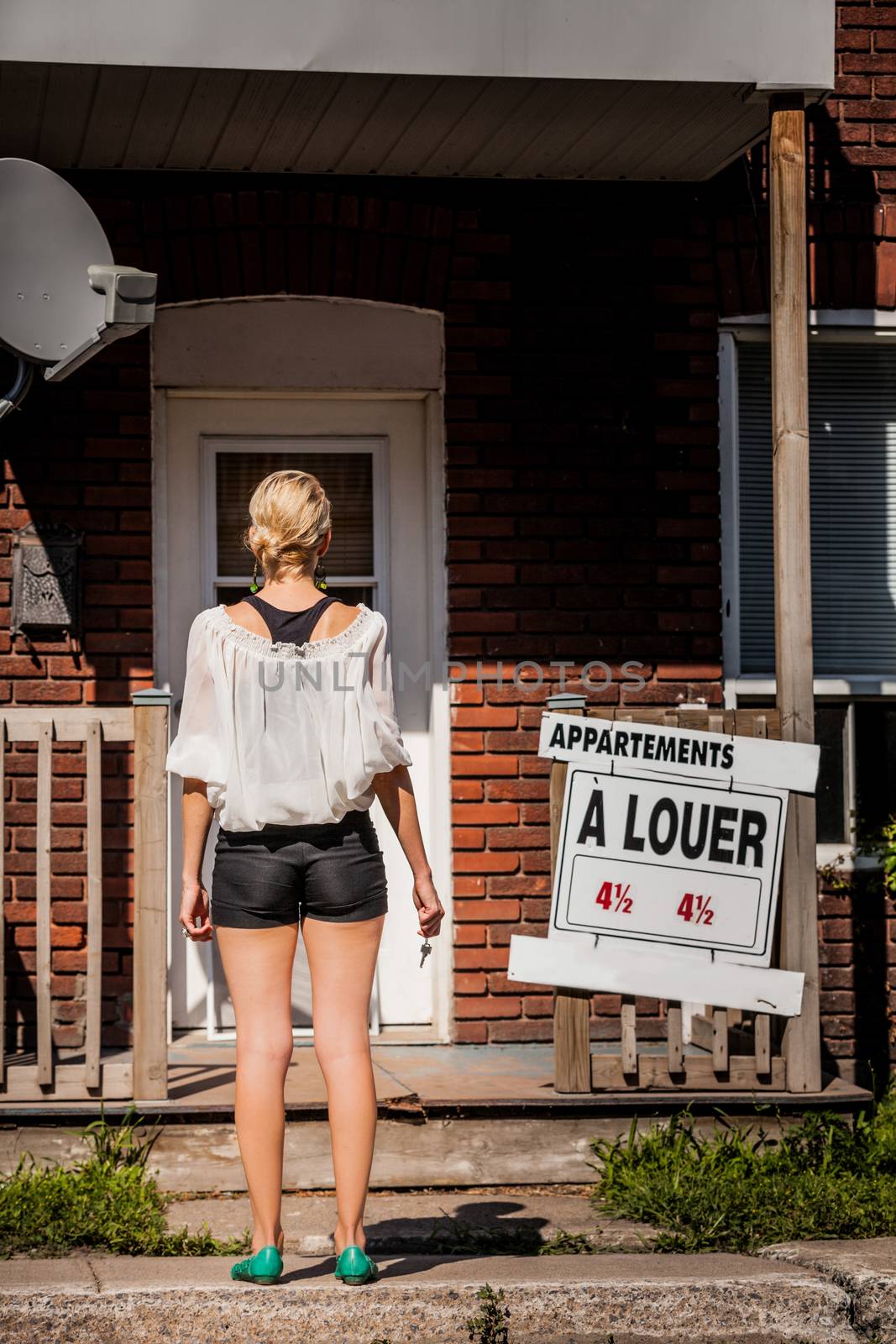 Young Woman standing in front of her new apartment by aetb