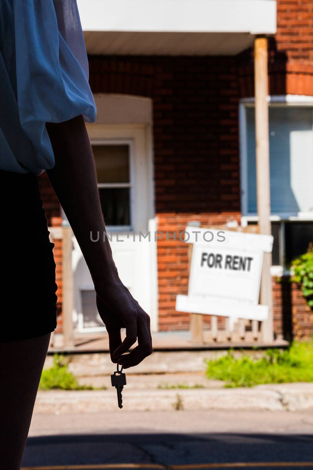 Young Woman standing with keys in front of her new apartment