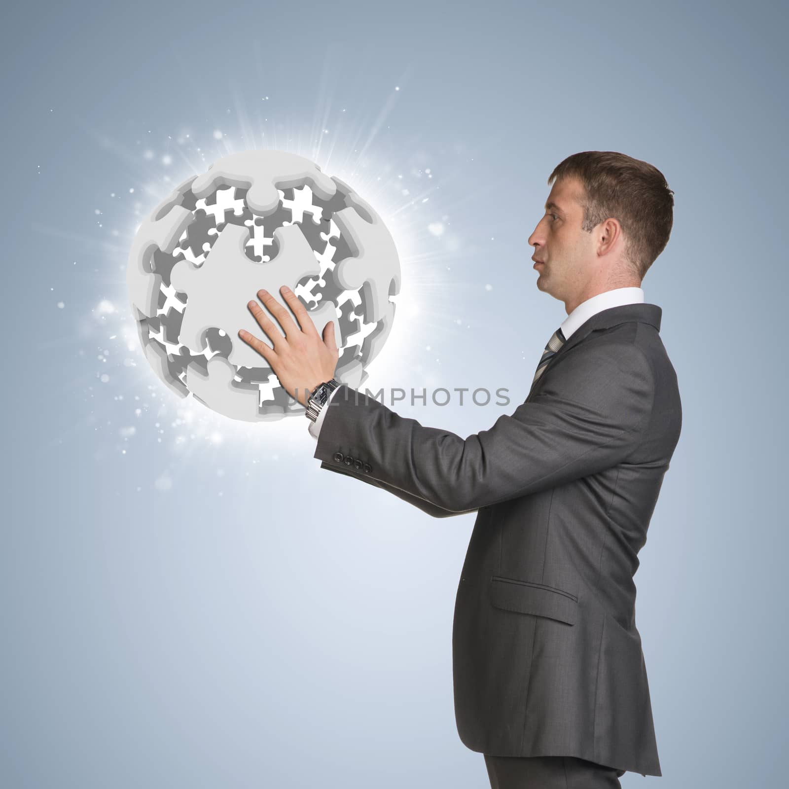 Businessman in suit hold jigsaw puzzle sphere. Blue background