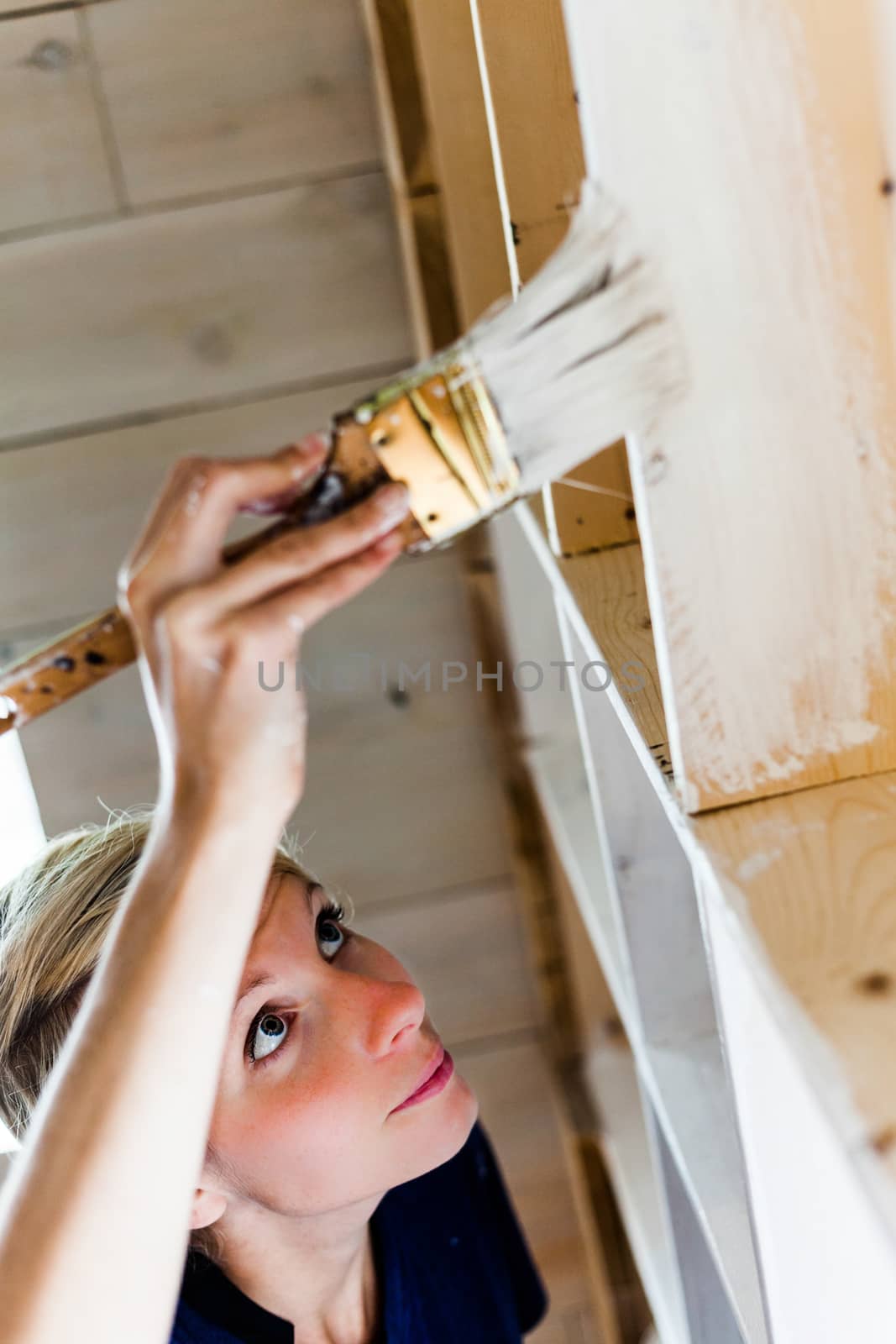Real Home Renovation (not studio) - Woman Applying White Paint on a Wood Library.