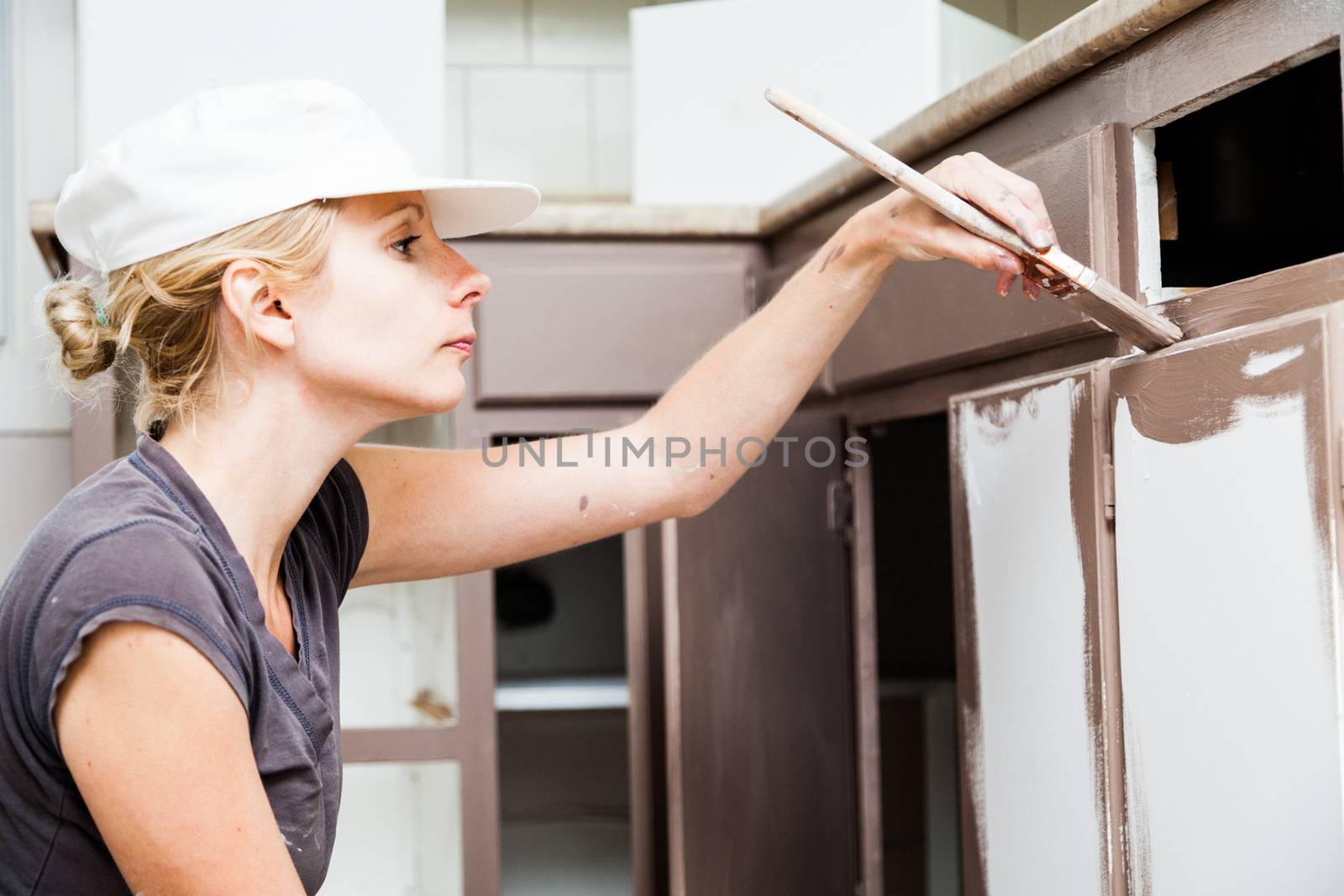 Closeup of Woman Painting Kitchen Cabinets by aetb