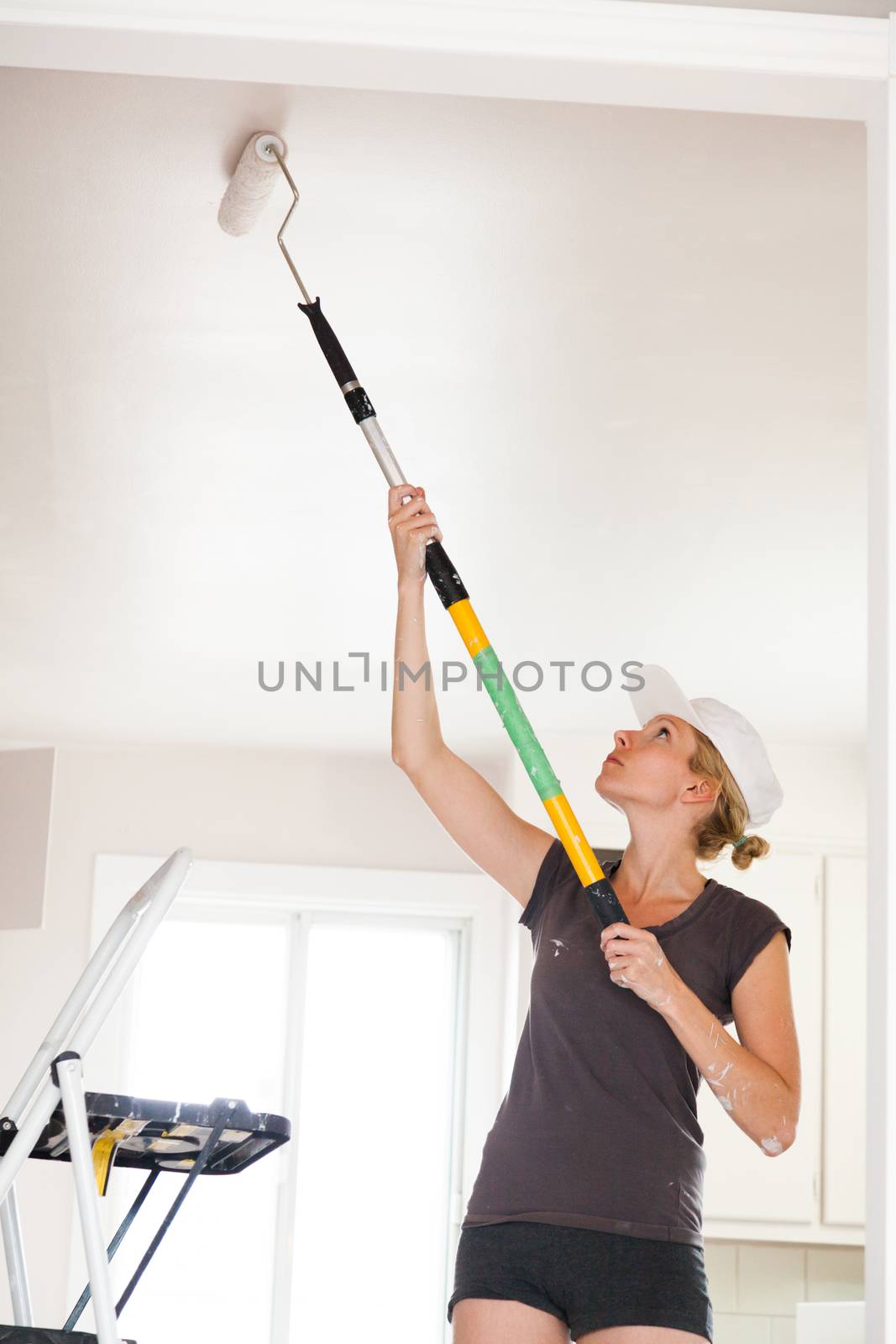 Closeup of Woman Holding Roller Pin and Painting the Ceiling