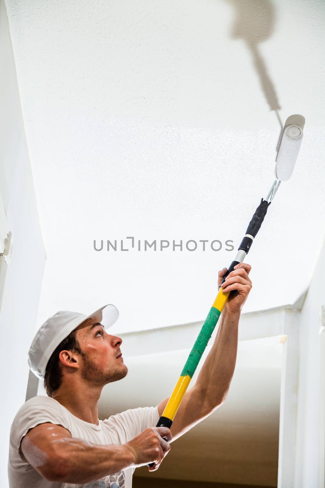 Closeup of Man Holding Roller Pin and Painting the Ceiling
