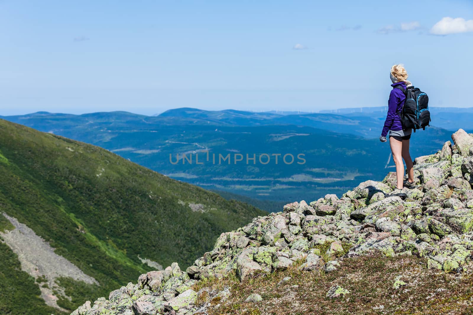 Young Woman with Backpack Looking at the View From the Top of the Hill