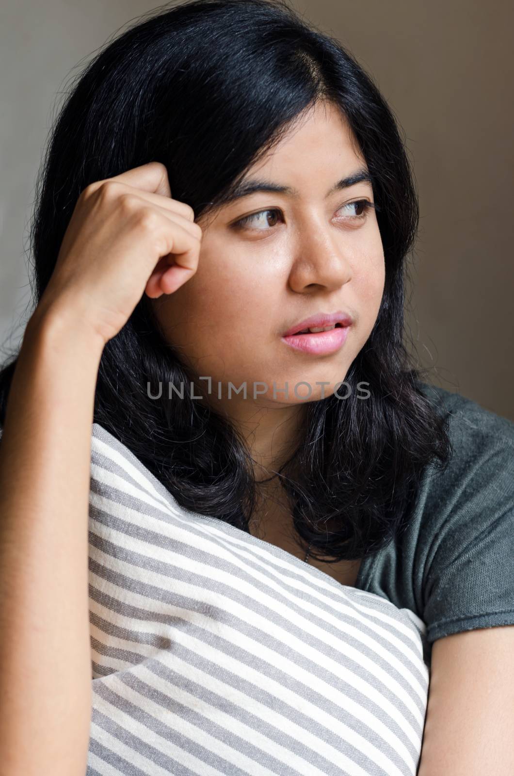 Asian woman holding pillow and thinking